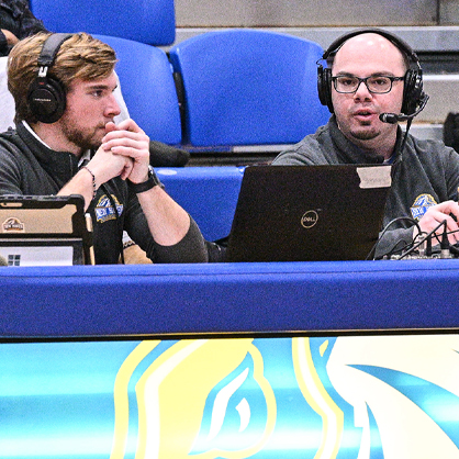 Student broadcasters call a basketball game on campus.
