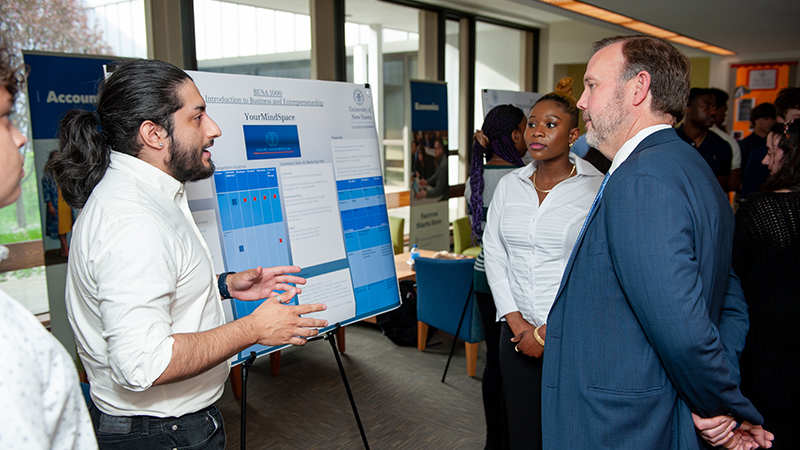 Students explain their proposed mental health app to Dean Brian Kench, Ph.D., dean of the Pompea College of Business.