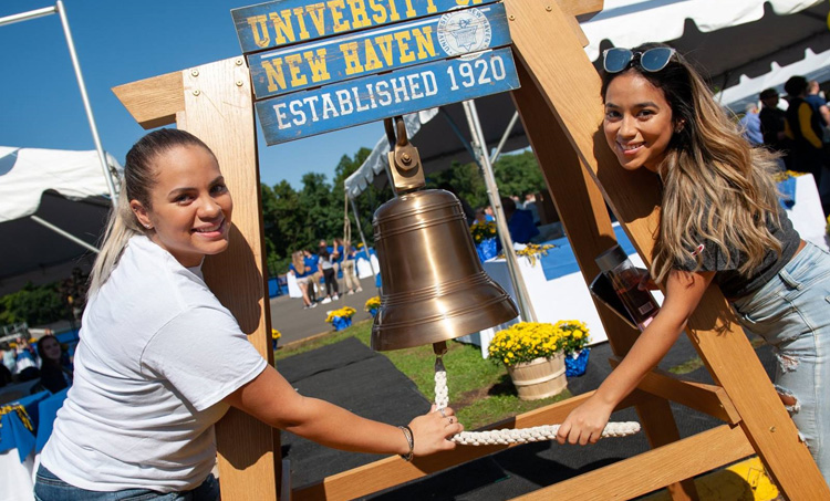 Two women ringing the Alumni Bell at Commencement