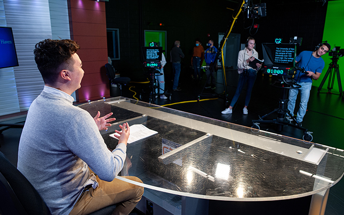 Student behind the news desk, training as an anchor.