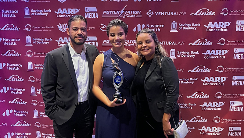 Julia Clara Ferreira ’27 (center) with her parents the night she accepted her award.