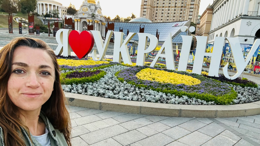 Dr. Olena Lennon on Maidan Nezalezhnosti (Independence Square) in Kyiv, which includes a grassroots memorial consisting of thousands of flags and photos, each representing a fallen Ukrainian soldier in Russia’s ongoing war against Ukraine. September, 2025. Photo credit: Olena Lennon