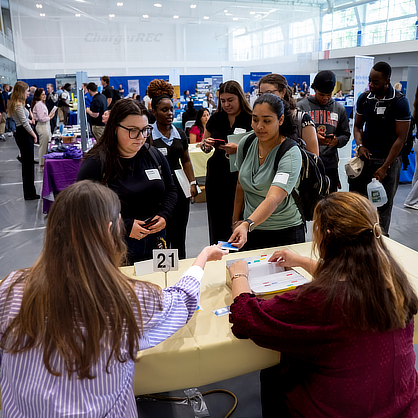 Student hands someone a business card at career fair