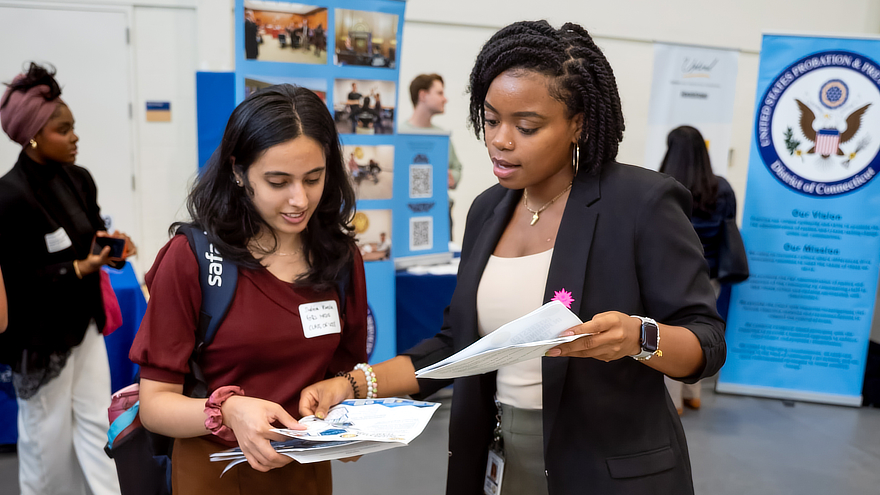 Two women looking at papers at career fair