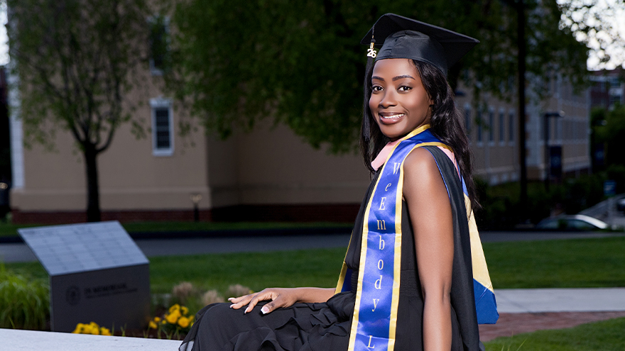 Jamesha Barrett poses on campus in her cap and gown.