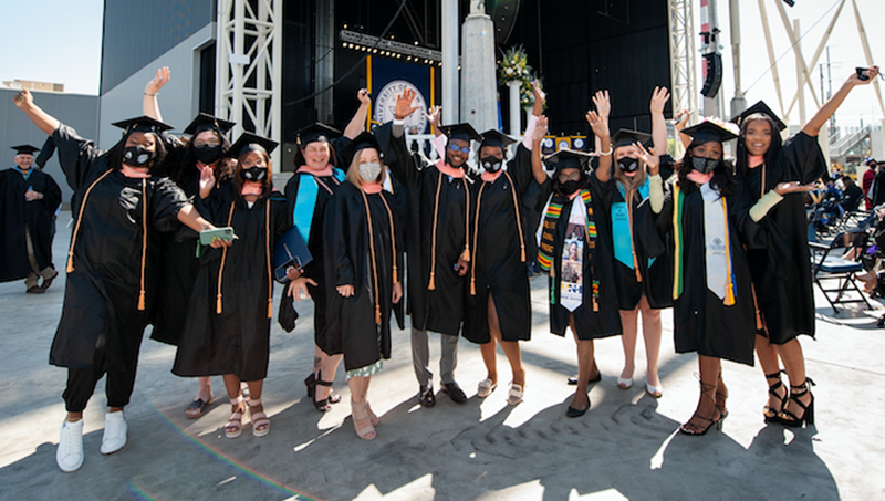 Students in their caps and gowns pose for a photo.