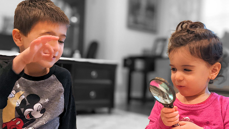 Two children holding a magnifying glass.