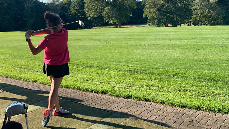 Emily Florin ’26 takes a swing with a golf club.