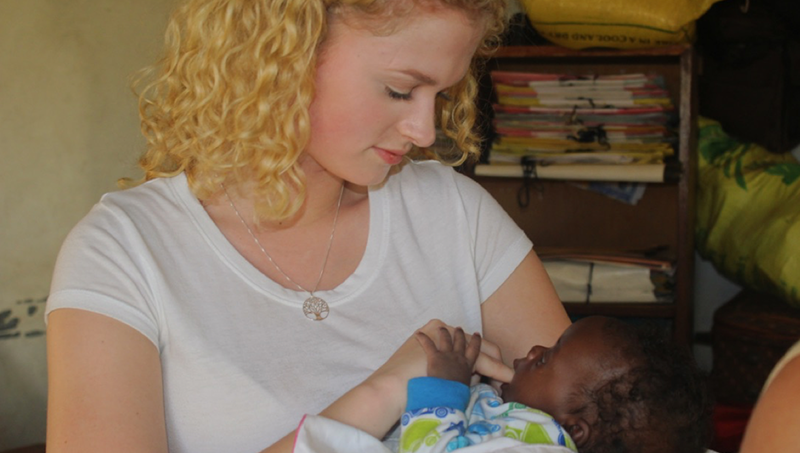 Image of Laney Phillips caring for a baby in Uganda.