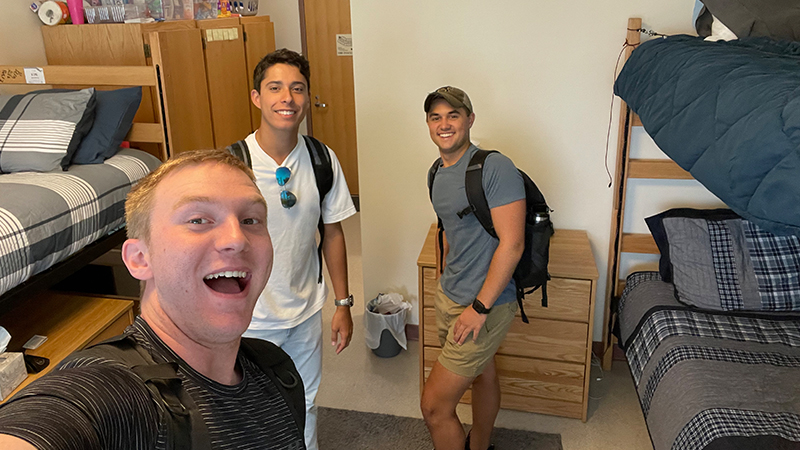 Three roomates pose for a photo in their dorm.