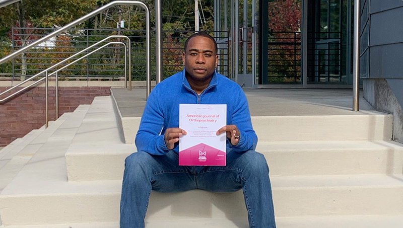 Kendell Coker, Ph.D., J.D. holding an issue of American Journal of Orthopsychiatry.