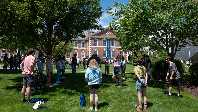 Students and orientation leaders play a game on the lawn.